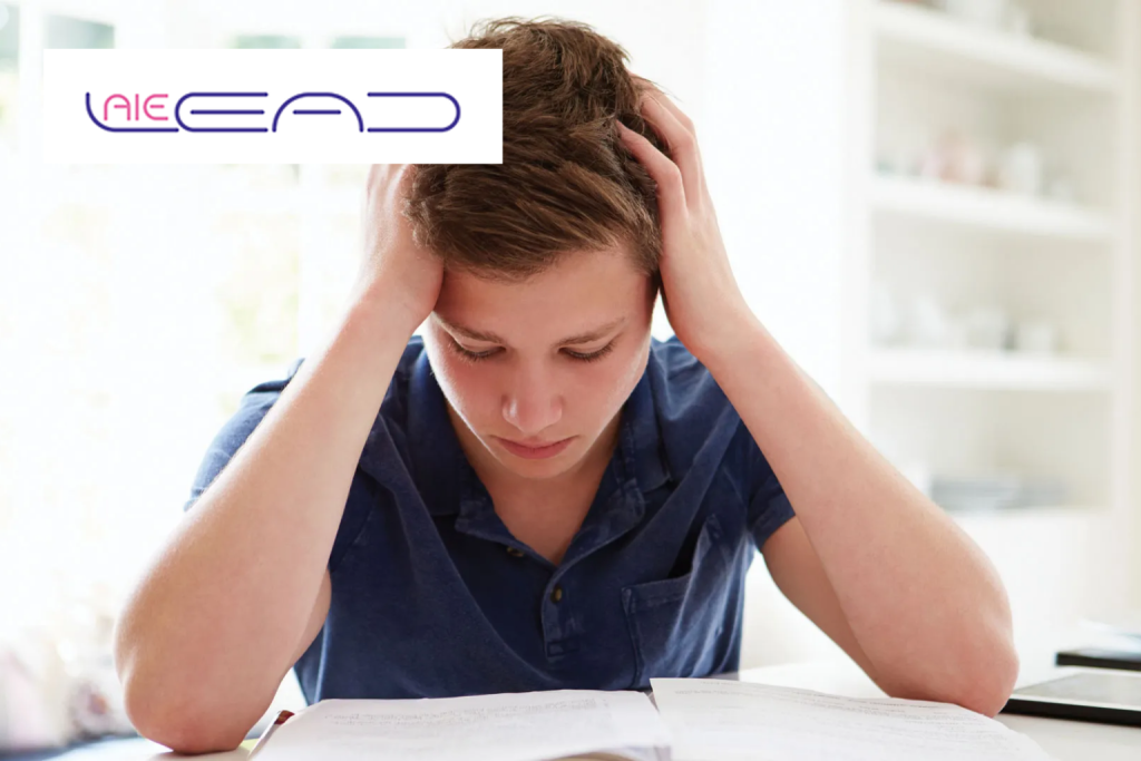 A teenage boy holding his head in his hands over his schoolwork, looking unsure of himself – AïeLEAD